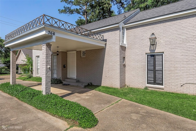 entrance to property with brick siding and a balcony