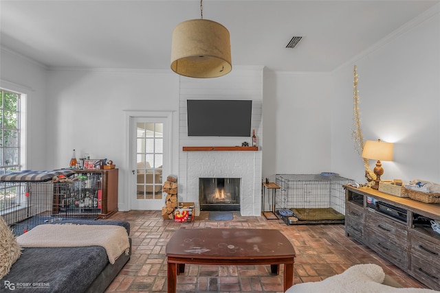 living room with brick floors, crown molding, and a brick fireplace