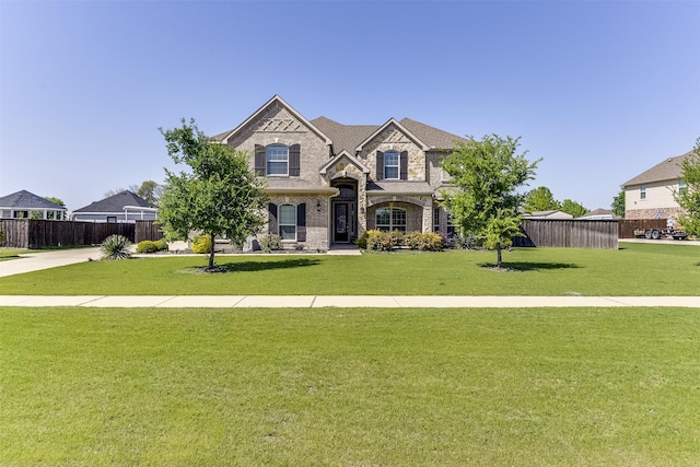 craftsman house featuring brick siding, a front lawn, fence, and stone siding