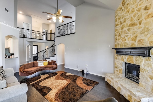 living area featuring high vaulted ceiling, a ceiling fan, arched walkways, a fireplace, and visible vents