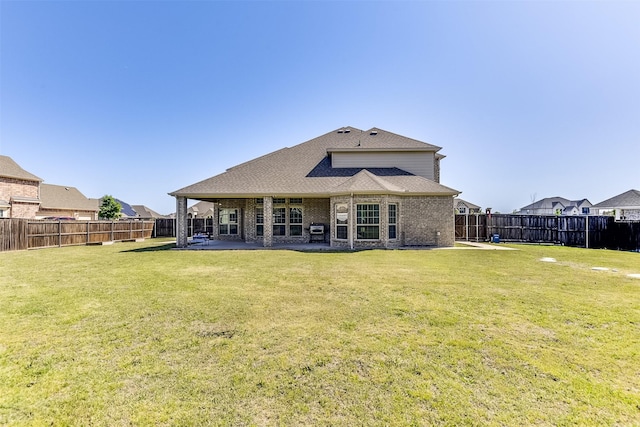 rear view of property with a lawn, a fenced backyard, brick siding, and a patio area