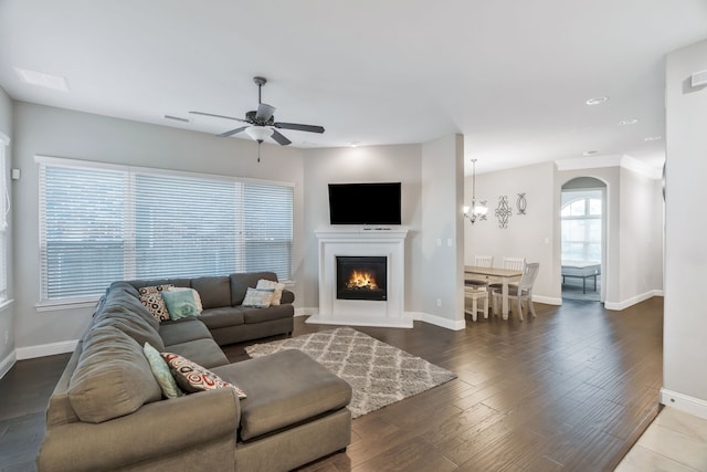 living room featuring a warm lit fireplace, visible vents, a ceiling fan, and baseboards