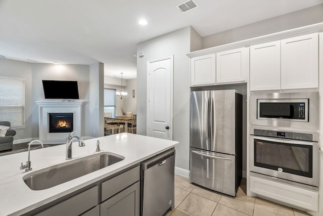 kitchen featuring light countertops, visible vents, a sink, appliances with stainless steel finishes, and open floor plan