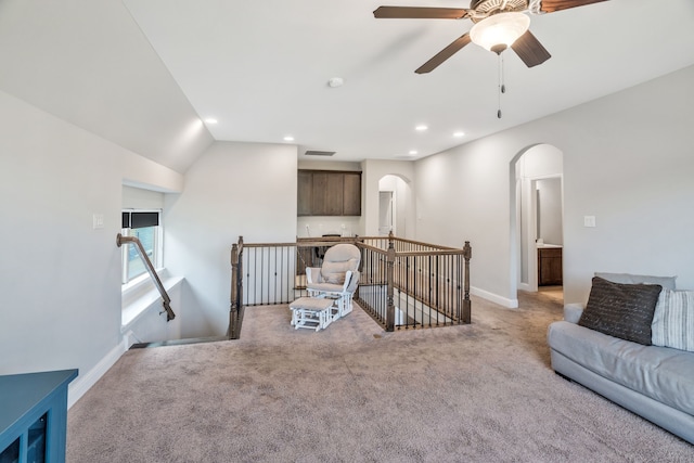living area with arched walkways, visible vents, light colored carpet, and ceiling fan