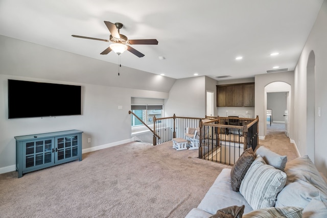 living area featuring a ceiling fan, arched walkways, light colored carpet, baseboards, and visible vents