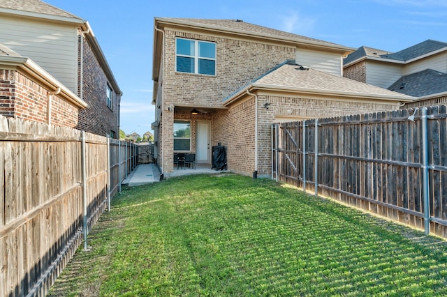 back of house featuring a fenced backyard, brick siding, a ceiling fan, a yard, and a patio