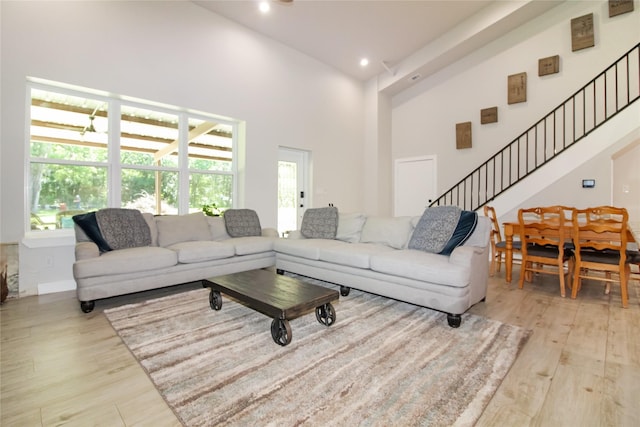 living room with high vaulted ceiling, plenty of natural light, and light wood-style flooring