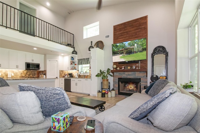 living room with recessed lighting, a stone fireplace, visible vents, light wood-style flooring, and high vaulted ceiling