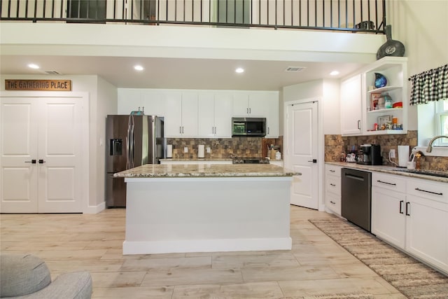 kitchen featuring open shelves, decorative backsplash, a sink, and appliances with stainless steel finishes