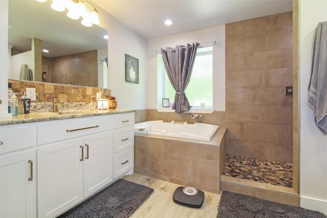 bathroom featuring a garden tub, wood finished floors, vanity, walk in shower, and recessed lighting