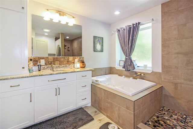 full bath with a bath, a tile shower, vanity, and wood finished floors
