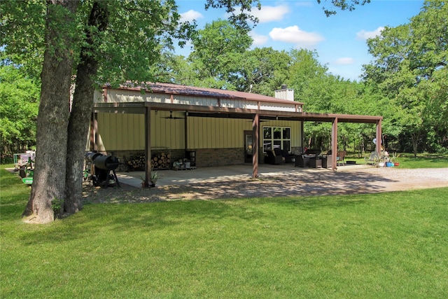 rear view of property with a carport, a chimney, a yard, and an outbuilding