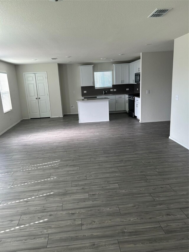 16033 Rein Ave, Haslet, TX 76052 - unfurnished living room with visible vents, baseboards, a textured ceiling, and dark wood-style floors