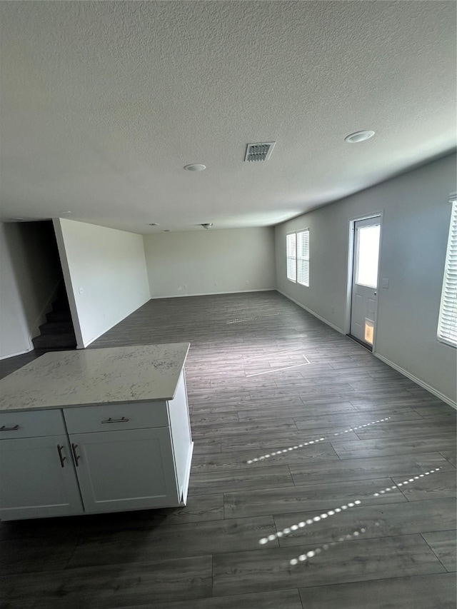 16033 Rein Ave, Haslet, TX 76052 - unfurnished living room featuring a textured ceiling, dark wood-style flooring, baseboards, visible vents, and stairway