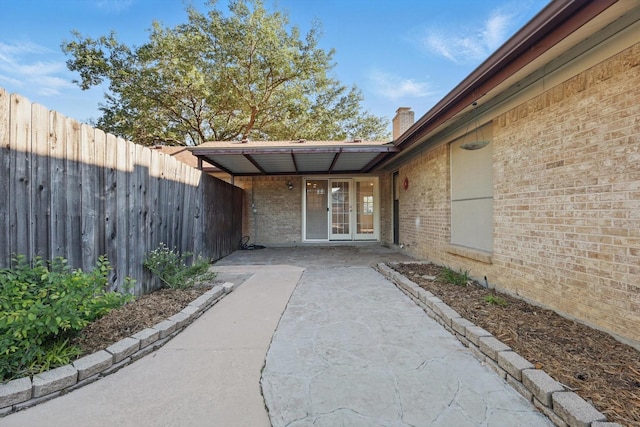 3141 La Kenta Cir, Farmers Branch, TX 75234 - doorway to property featuring fence, french doors, brick siding, and a chimney