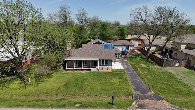 back of house featuring a lawn, driveway, a shingled roof, fence, and a porch