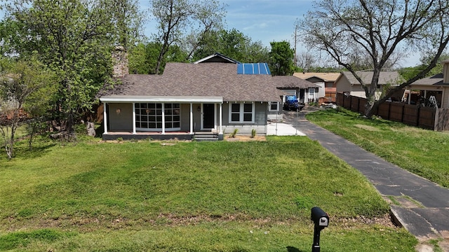 view of front of home with fence, roof with shingles, aphalt driveway, and a front yard