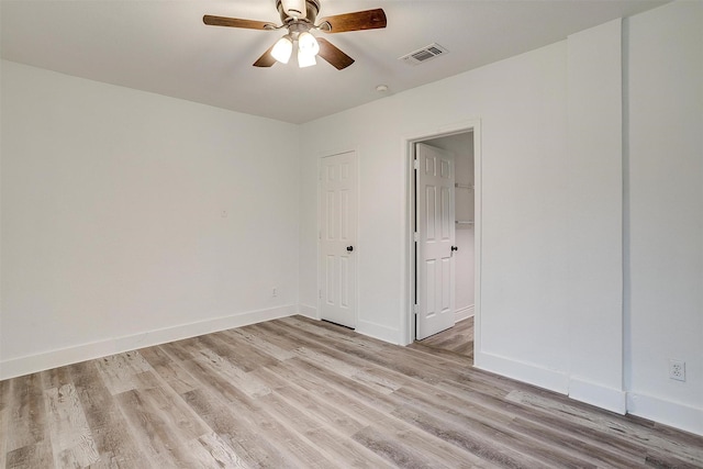 unfurnished room featuring light wood-style floors, visible vents, baseboards, and ceiling fan