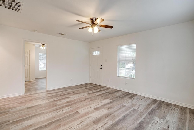 spare room featuring light wood-style floors, visible vents, a ceiling fan, and baseboards