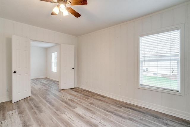 empty room featuring ceiling fan, baseboards, ornamental molding, and light wood-style flooring