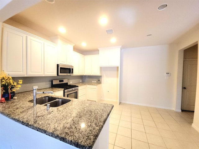 4223 Cascade Sky Dr, Arlington, TX 76005 - kitchen with light stone counters, appliances with stainless steel finishes, backsplash, a sink, and a peninsula