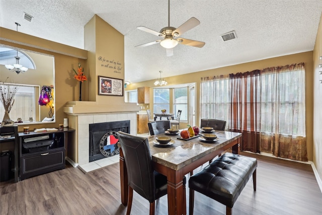 dining room with a textured ceiling, visible vents, wood finished floors, and ceiling fan with notable chandelier