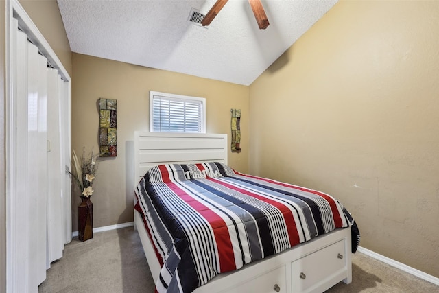 bedroom featuring a closet, light carpet, baseboards, a ceiling fan, and a textured ceiling