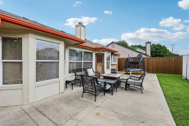 view of patio / terrace featuring an outdoor living space, a trampoline, and a fenced backyard