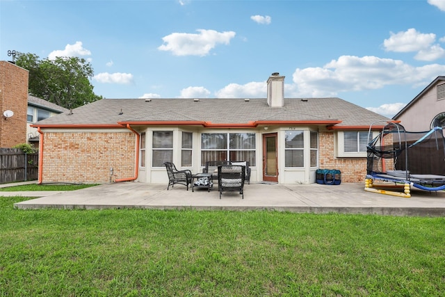 back of house with a trampoline, brick siding, fence, and a patio area