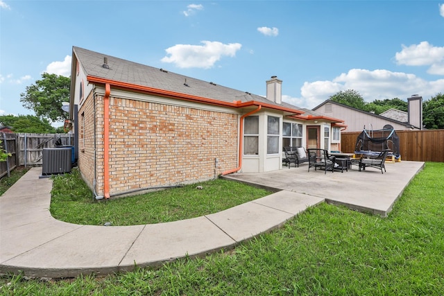 rear view of property featuring a patio, a yard, a fenced backyard, cooling unit, and a chimney