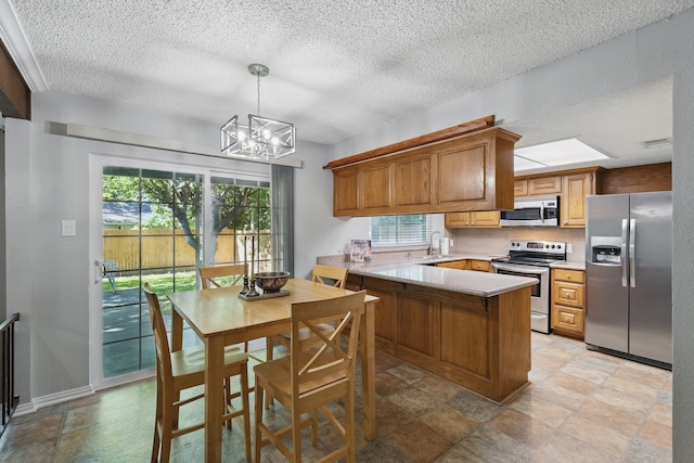kitchen with a peninsula, stainless steel appliances, a textured ceiling, and plenty of natural light