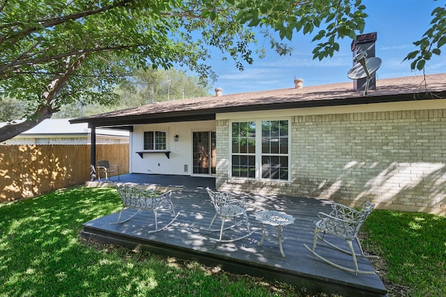 back of property with fence, a yard, and a deck