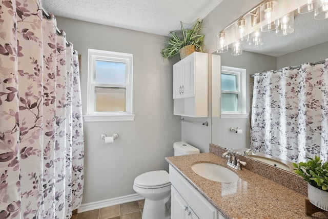 bathroom featuring toilet, vanity, a textured ceiling, and a healthy amount of sunlight