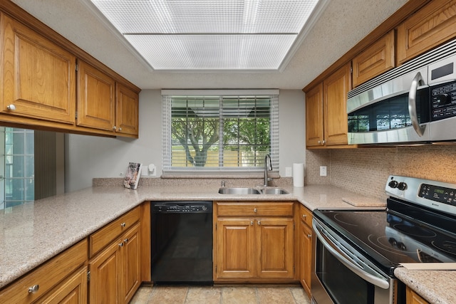 kitchen featuring decorative backsplash, brown cabinetry, a sink, and appliances with stainless steel finishes