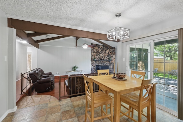 dining area with baseboards, a stone fireplace, a textured ceiling, and ceiling fan with notable chandelier
