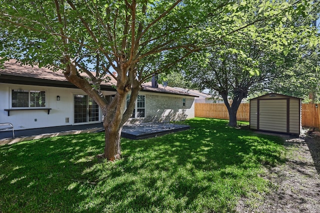 view of yard featuring a patio area, a fenced backyard, an outbuilding, and a storage shed