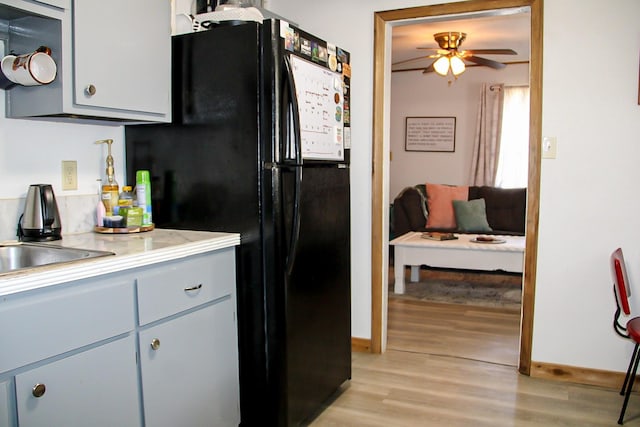 kitchen featuring light wood-type flooring, freestanding refrigerator, baseboards, a ceiling fan, and light countertops