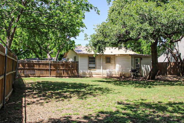 rear view of house featuring a yard, a fenced backyard, and metal roof