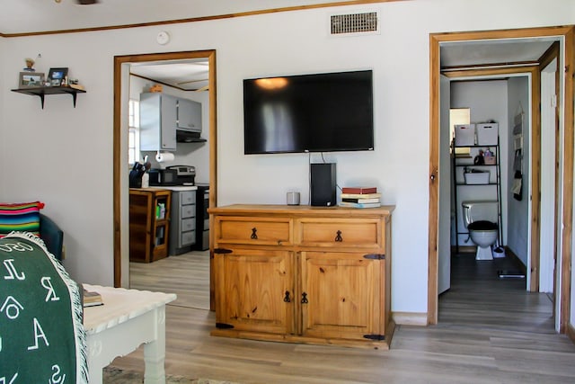bedroom with light wood-type flooring, visible vents, and ornamental molding
