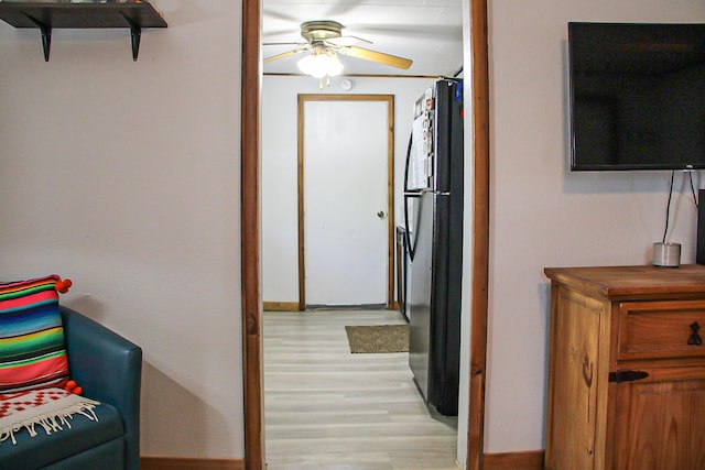 hallway featuring light wood finished floors and baseboards