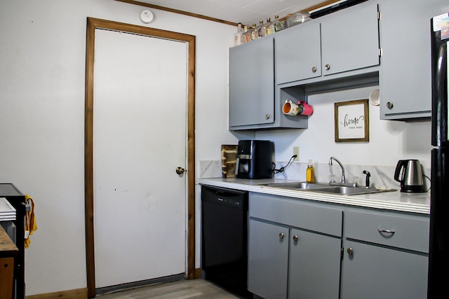 kitchen with a sink, light wood-style floors, black dishwasher, gray cabinetry, and light countertops