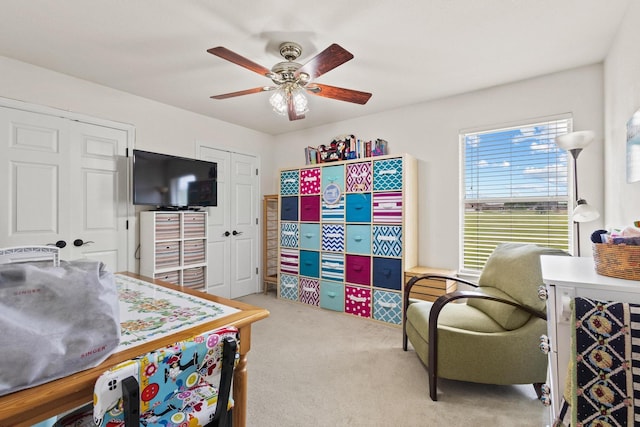 bedroom featuring two closets, light carpet, and a ceiling fan