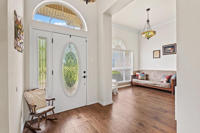 foyer featuring baseboards, crown molding, hardwood / wood-style floors, and plenty of natural light