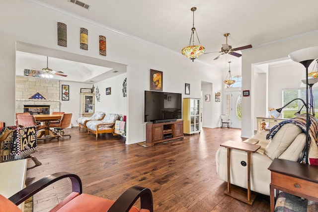 living area with a fireplace, crown molding, visible vents, and a ceiling fan