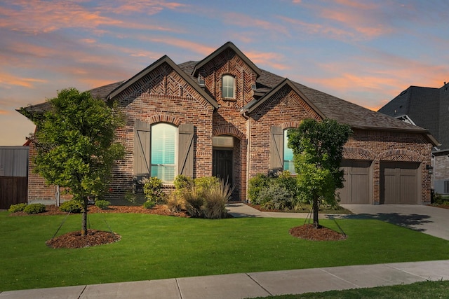 french provincial home with brick siding, driveway, a front lawn, and central AC unit