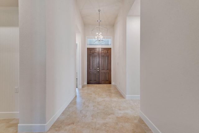 hall featuring an inviting chandelier and baseboards