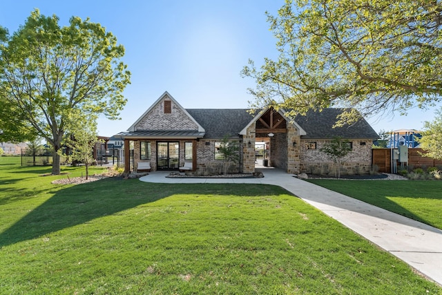 view of front of house with stone siding, fence, a front yard, brick siding, and a standing seam roof