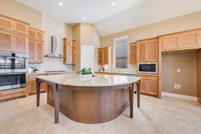 kitchen with backsplash, wall chimney exhaust hood, appliances with stainless steel finishes, and a center island