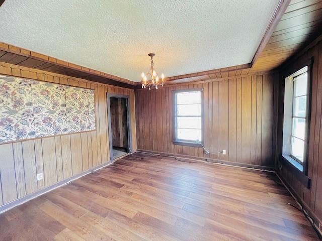 438 Atkins St, Sulphur Springs, TX 75482 - empty room featuring a chandelier, wooden walls, a textured ceiling, and baseboards