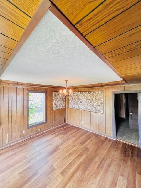 438 Atkins St, Sulphur Springs, TX 75482 - additional living space featuring light wood finished floors, baseboards, wood walls, and a notable chandelier